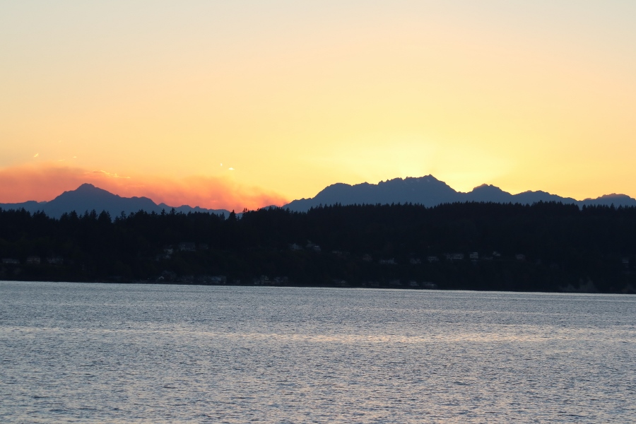 The sun drops behind the Olympic Mountain Range